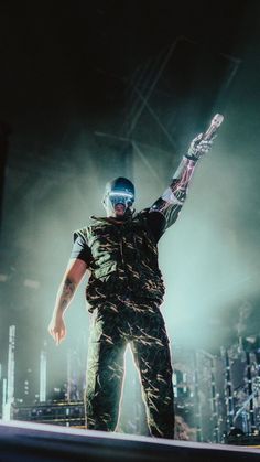 a man standing on top of a stage with his arms in the air and one hand up