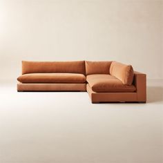 a large sectional couch sitting on top of a white floor next to a brown ottoman