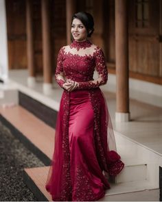 a woman in a long red dress standing on steps with her hand on her hip