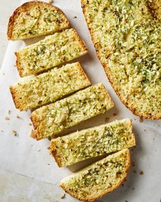 slices of bread with pesto on top sitting on a piece of white parchment paper