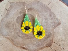 a pair of yellow and green beaded earrings sitting on top of a piece of wood