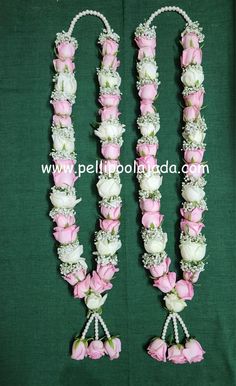 two pink and white flowers are attached to the side of a green cloth covered table