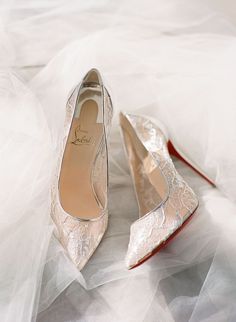 a pair of white shoes sitting on top of a bed covered in tulle skirt