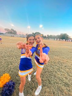 two cheerleaders giving the peace sign at a football game