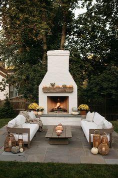 an outdoor fireplace with white couches and pillows