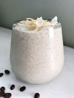 a glass filled with food sitting on top of a table next to some coffee beans