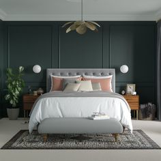 a bedroom with green walls, white bedding and a gray upholstered bench