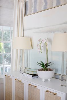 a white table topped with a plant and two lamps