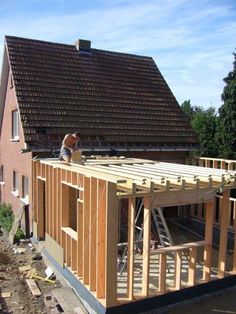 a man is working on the roof of a house that's being built with wooden framing