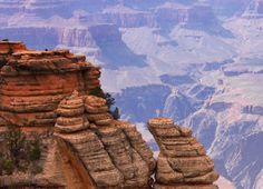 a man standing on the edge of a cliff looking down at some mountains and cliffs