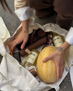 a person holding a large watermelon in their hand and some bottles on the ground