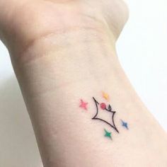 a small tattoo on the wrist of a woman's left arm with stars around it