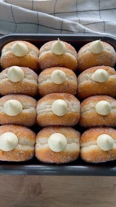 there are many doughnuts with icing in a tray on the table, ready to be eaten