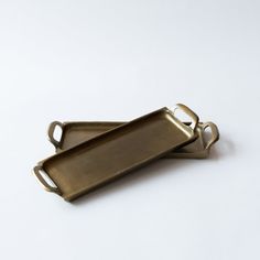 two brass serving trays with handles on each side, one holding a bottle opener