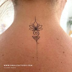 the back of a woman's neck with a flower tattoo on it