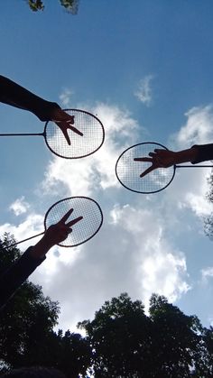 three people are holding up their hands to catch frisbees