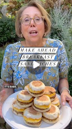 a woman holding a plate with pancakes on it and the words make ahead breakfast sandwiches