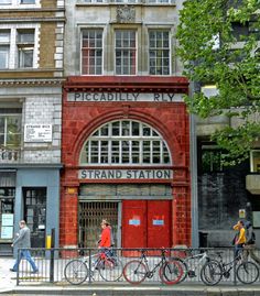 people walking and riding bikes in front of a red brick building