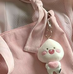 a pink purse with a white and pink keychain hanging from it's side