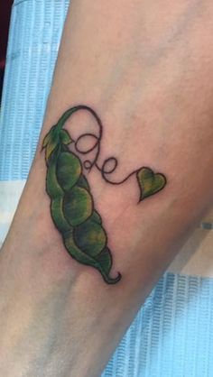 a person with a tattoo on their leg that has a green pea pod in it