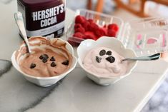 two bowls filled with ice cream and raspberries next to a can of hershey's cocoa