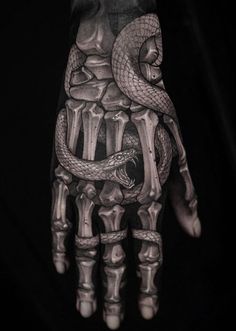 a hand with a tattoo on it and a snake wrapped around the wrist, in black and white