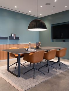 a dining room table with four chairs and a television mounted on the wall behind it