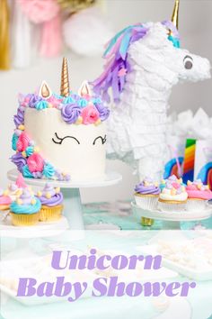 a table topped with cakes and cupcakes covered in frosting next to a unicorn figurine