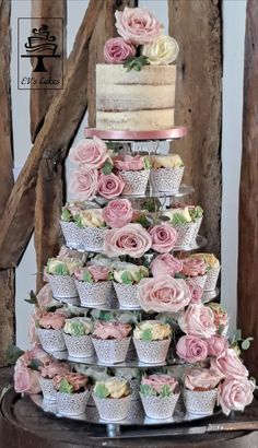 a wedding cake made out of cupcakes with pink flowers on top is displayed