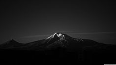 a black and white photo of the top of a mountain at night with clouds in the sky