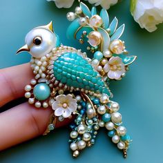 a close up of a person's hand holding a brooch with flowers and pearls