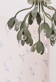 a green chandelier hanging from the ceiling in a room with pink wallpaper