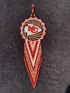 a red and white beaded ornament hanging from a hook on a wall