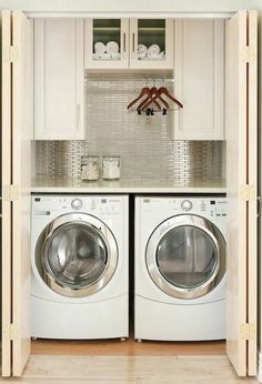 a washer and dryer in a small room with white cupboards above them