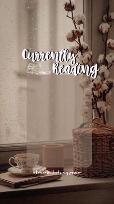 a coffee cup sitting on top of a window sill next to a vase with cotton flowers