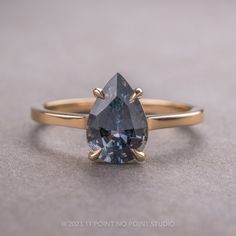 a blue diamond ring sitting on top of a gray surface with two gold rings around it