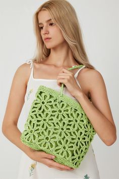 a woman holding a green crochet bag