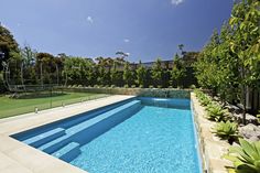 an empty swimming pool in the middle of a backyard with grass and trees around it