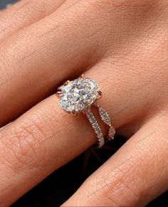 a woman's hand with a diamond ring on top of her finger and an engagement band