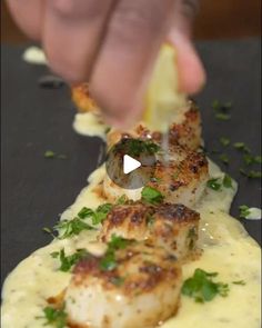 someone is dipping some kind of food on top of something yellow and white with parsley