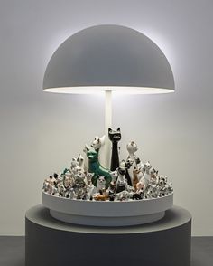 a lamp that is sitting on top of a table with cats and dogs around it