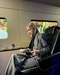 a woman sitting on a train looking at her tablet