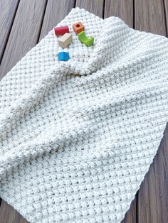 a white crocheted blanket laying on top of a wooden floor next to toys