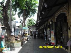 people are walking down the sidewalk in front of shops and stores on a sunny day