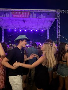 two people dancing in front of a crowd at a party with purple lights on the stage