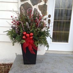 a christmas planter with candy canes and greenery in front of a house