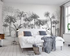 a bedroom with palm trees painted on the wall and white bed in front of it