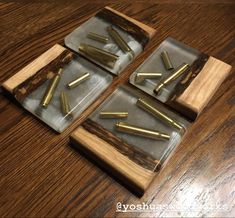 four pieces of wood with brass nails in them sitting on a table next to a cup