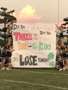 the cheerleaders are holding up a sign for their team to perform on the field