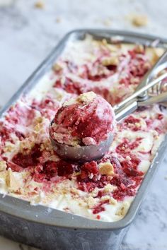 a scoop of ice cream sitting on top of a metal pan filled with raspberries